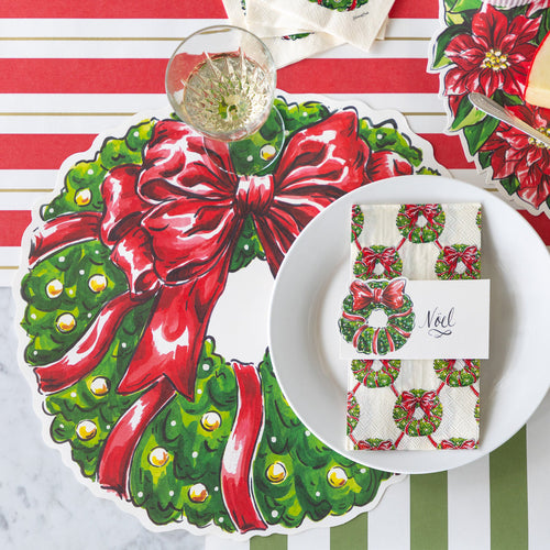 Christmas-themed table setting with wreath and bow design on placemats and napkins.