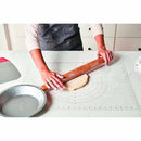 Person rolling dough on a silicone baking mat with a rolling pin.