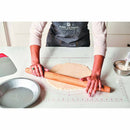 Person rolling out dough with a wooden rolling pin on a kitchen counter.