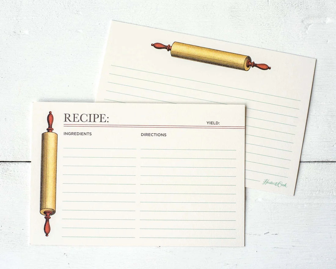 A set of cream-colored recipe cards with lined writing sections and an illustration of a gold rolling pin, shown on a white wood background.