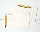 A set of cream-colored recipe cards with lined writing sections and an illustration of a gold rolling pin, shown on a white wood background.