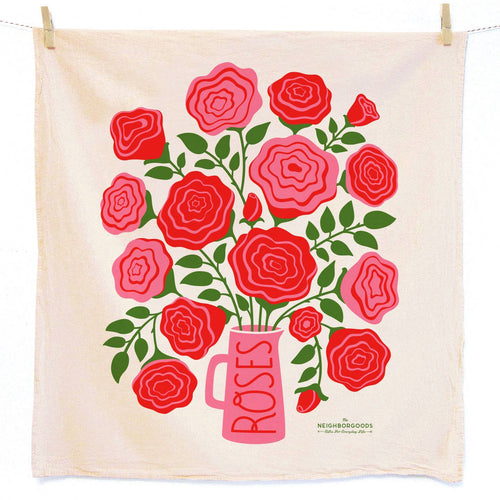 Beige kitchen towel with red roses and a pink vase printed on it, hanging on a line.
