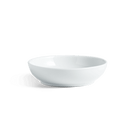A white porcelain sauce bowl on a green background.