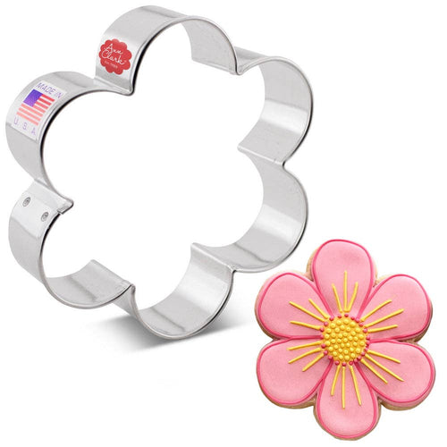 Flower-shaped cookie cutter with a decorated flower cookie on a white background
