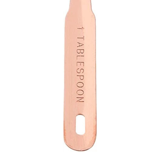 A single copper-colored measuring spoon with '1 TABLESPOON' engraved vertically on the handle, shown against a plain white background.