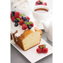 Slice of cake with berries on a plate next to a cup of coffee.