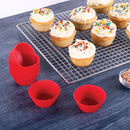Silicone cupcake liners on a blue surface with cupcakes on a cooling rack.