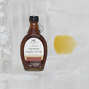 Bottle of Vermont maple syrup with a label on a textured gray background