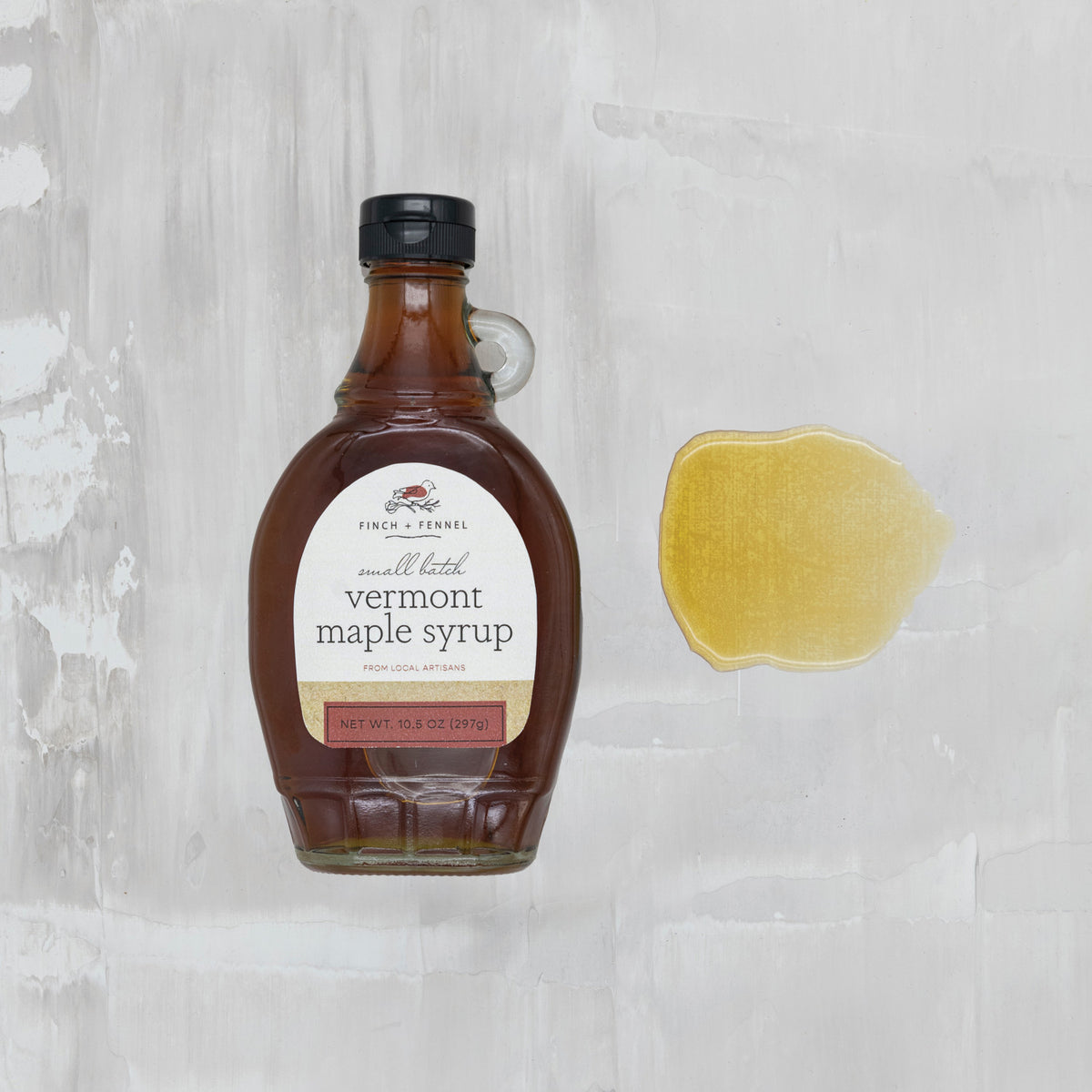 Bottle of Vermont maple syrup with a label on a textured gray background