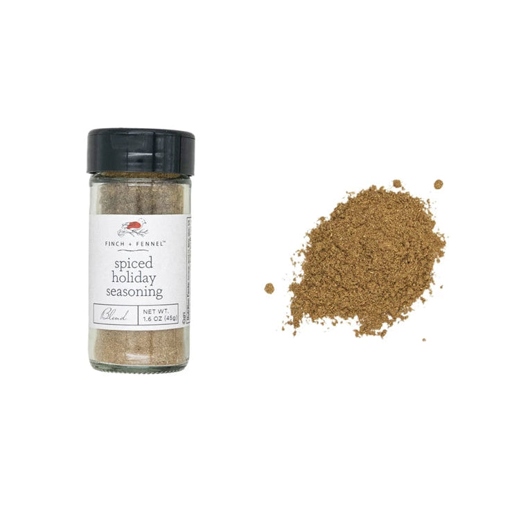 A bottle of Finch and Fennel Spiced Holiday Seasoning with a small pile of the spice next to it on a white background.