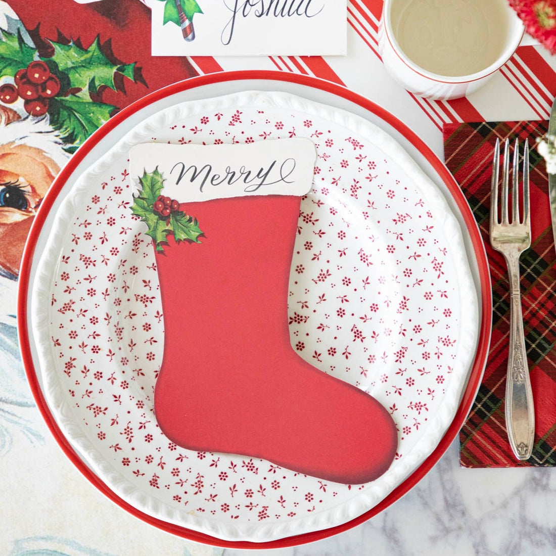 Christmas-themed place setting with a red stocking table accent on a white plate.