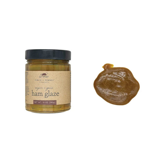 A jar of Finch & Fennel Sugar & Spice Ham Glaze next to a small amount of the glaze on a surface, showcasing the product's color and texture.