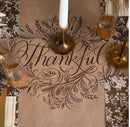 Table setting with 'Thankful' placemat, glasses, and candle.