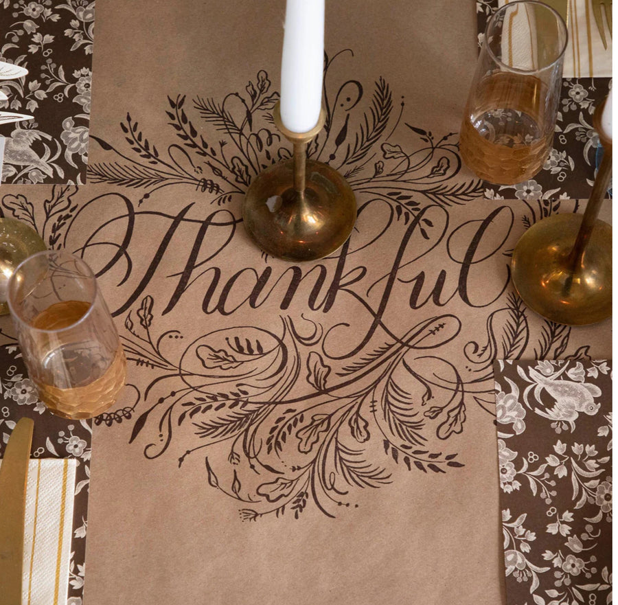 Table setting with 'Thankful' placemat, glasses, and candle.