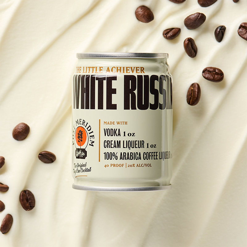 A single can of White Russian is centered on a warm cream background with scattered coffee beans around it. 