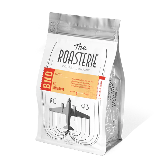A bag of Roasterie coffee called KC Kingdom Blend with an airplane on a white background.