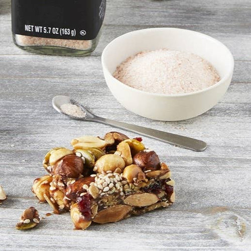 Nuts and seeds mix with a bowl of salt and spoon on a wooden surface