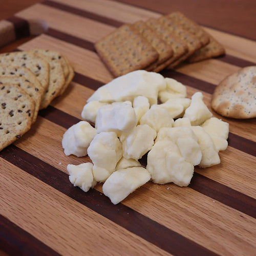 Cheese curds and crackers on a wooden cutting board