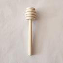 Wooden honey dipper on a light gray background