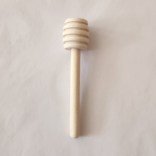 Wooden honey dipper on a light gray background