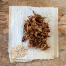 Shredded meat on a paper towel with BBQ spices a wooden background