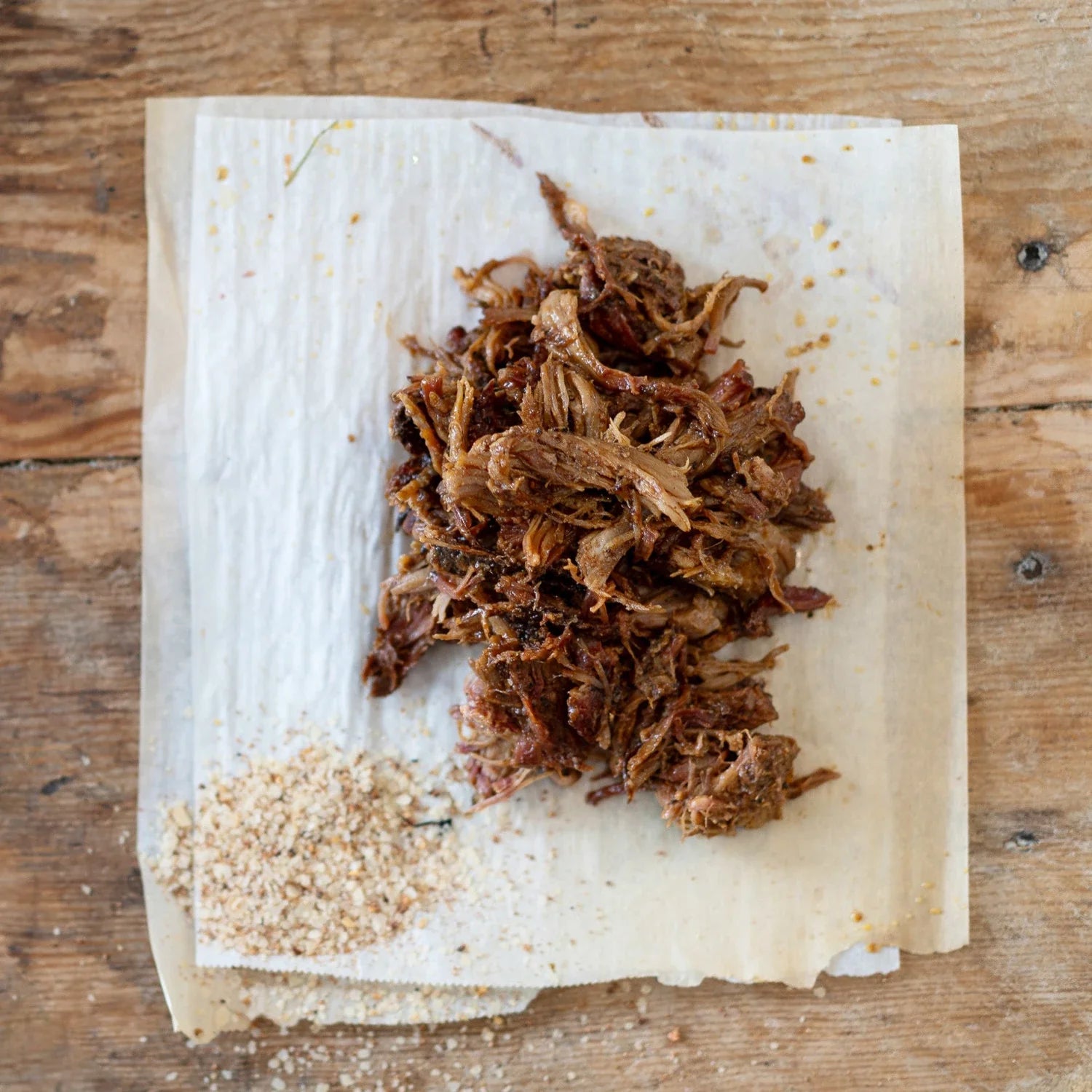 Shredded meat on a paper towel with BBQ spices a wooden background