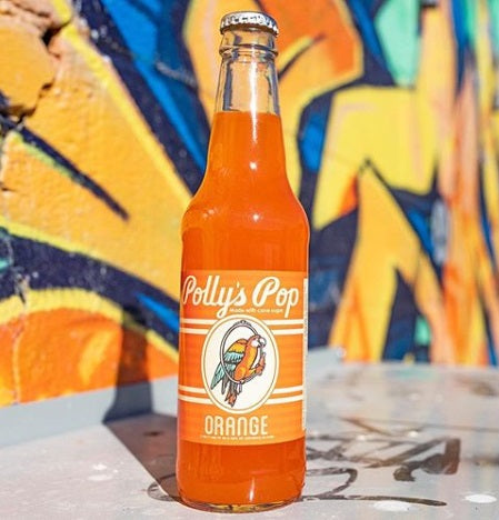 A bottle of orange flavored Polly's Pop against a graffiti background.