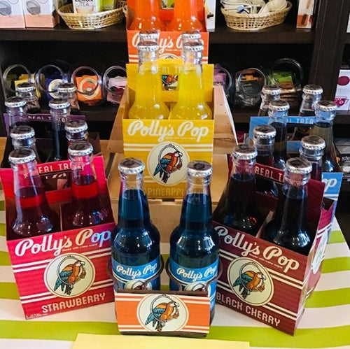 A display of Polly's Pop soda bottles in various flavors, organized in cases.