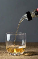A glass with liquid poured into it via a measured pourer.
