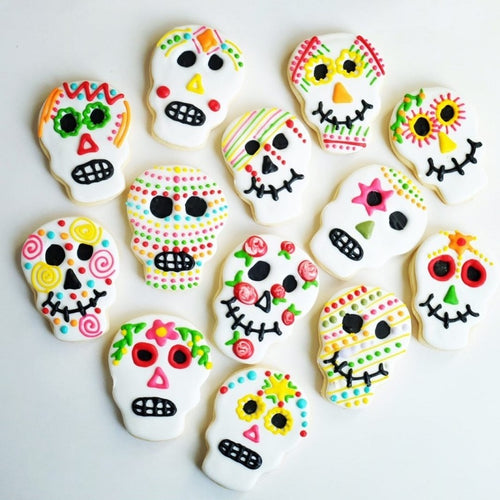 A collection of cookies in the shape of skulls and decorated to celebrate Dia de Los Muertos.