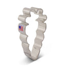 A silver stainless steel carrot-shaped cookie cutter made by Ann Clark, with a flag sticker indicating it is made in America.
