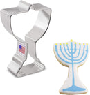 A silver cookie cutter in the shape of a Menorah, alongside a finished cookie with a blue and white icing design.