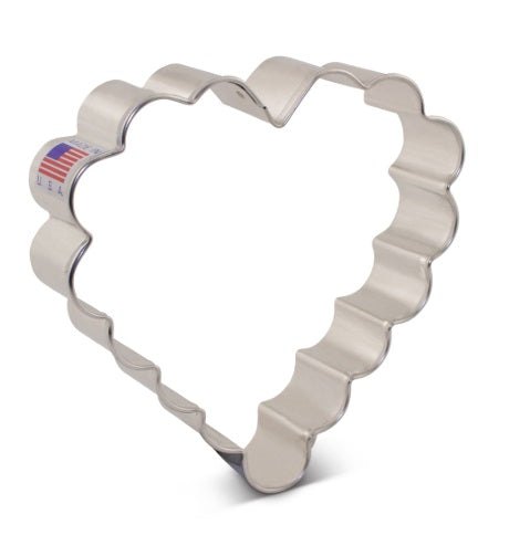 A metallic cookie cutter shaped like a scalloped heart with a 'made in USA' sticker.