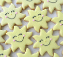 Several sun-shaped cookies with yellow icing and smiley faces.