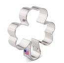 A stainless steel cookie cutter in the shape of a four leaf clover, commonly associated with St. Patrick's Day themes.