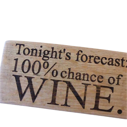 Wooden sign with engraved text 'Tonight's forecast: 100% chance of WINE' on a dark background