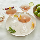 A serving tray with three cocktails on it on a white surface