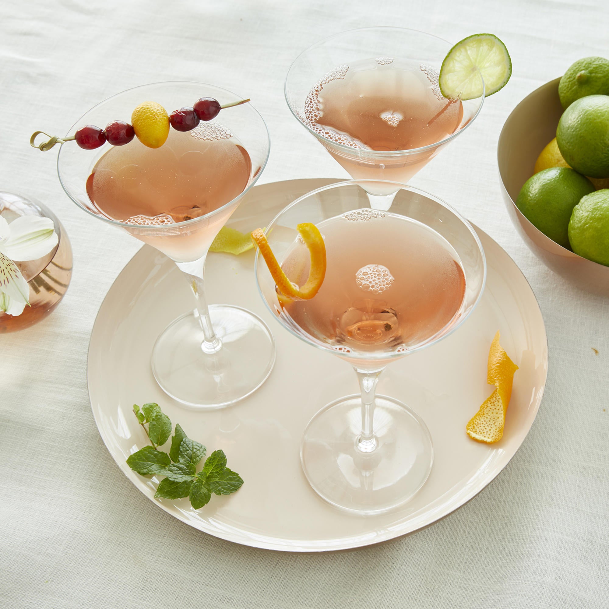A serving tray with three cocktails on it on a white surface