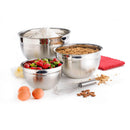 A set of three stainless steel mixing bowls of different sizes with a whisk in front and ingredients around them, displayed on a white background.