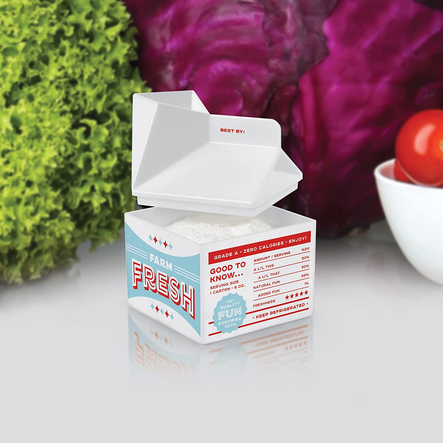 A fridge freshener showing the top can come off and baking soda can go inside with vegetables in the back, on a white surface.