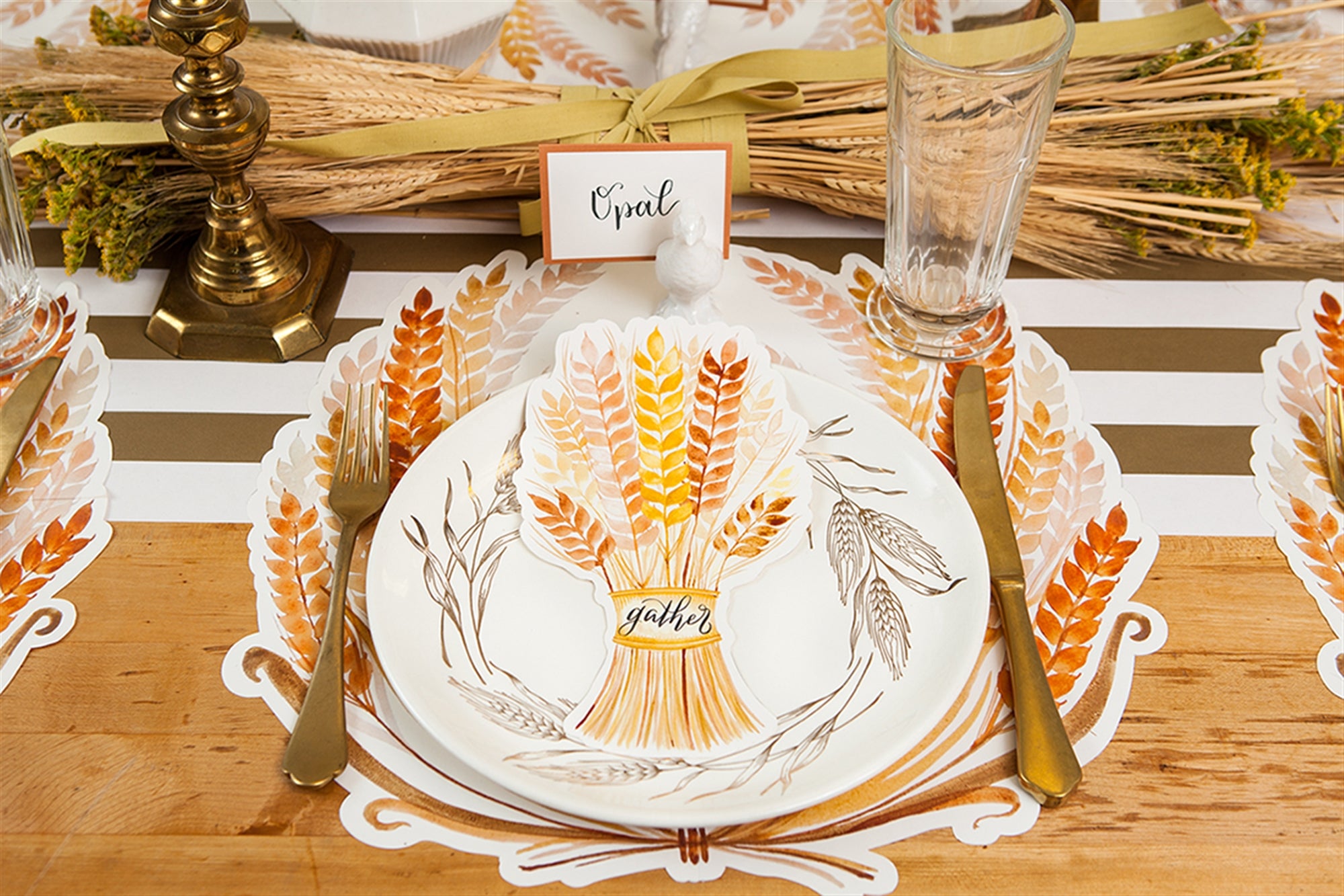 An autumn themed table display with gold utensils and harvest accents.