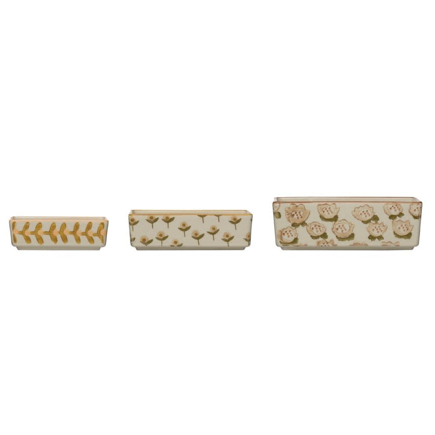 A set of three beige stoneware ramekins with a floral pattern, each with a different size.