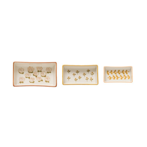 A set of three beige stoneware ramekins with a floral pattern, each with a different size.
