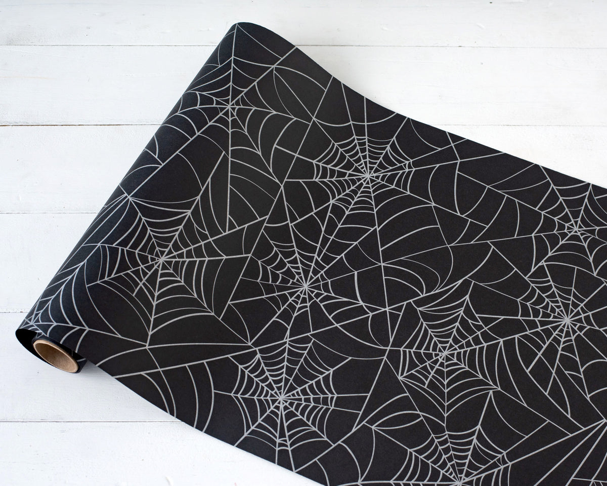 A roll of black table runner with a spider web pattern.