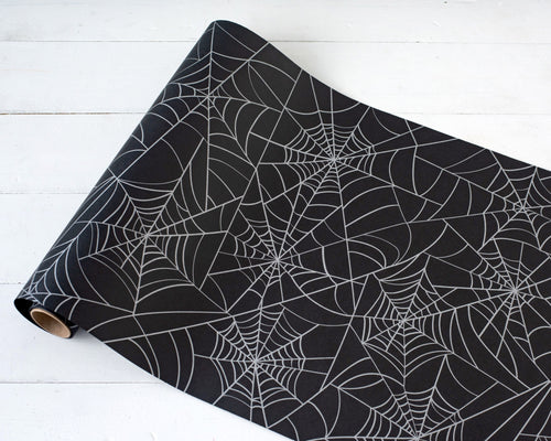 A roll of black table runner with a spider web pattern.