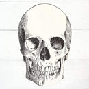 A die-cut paper placemat featuring a black and white skull design.