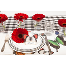 A place setting featuring black plaid table runner, butterfly placemats, plates, glasses with flowers, and a butterfly place card.