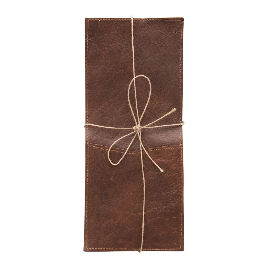 A brown leather cutlery sleeve with a tie and a loop for holding utensils.