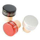 Three metallic bottle stoppers in black, red, and silver on a white background.