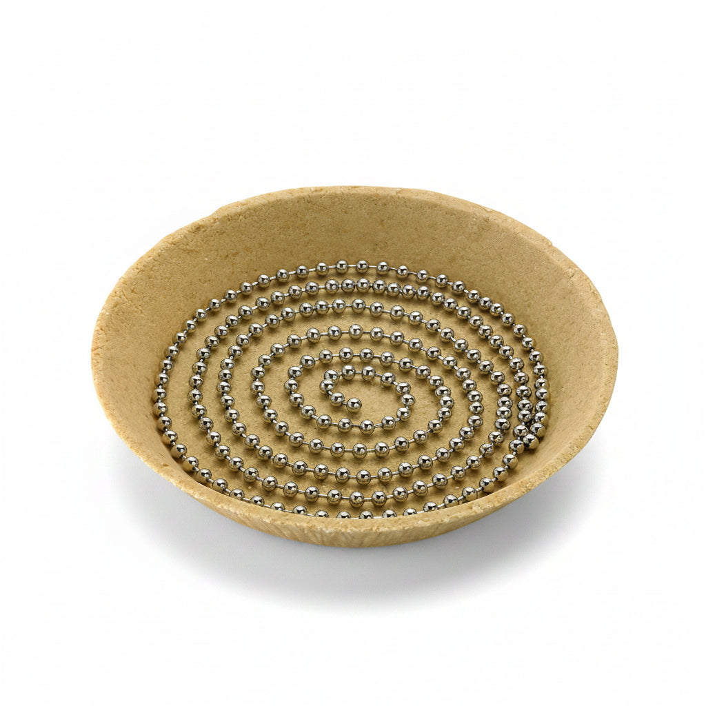 A stainless steel pie weight chain coiled inside of a pie crust on a white background.